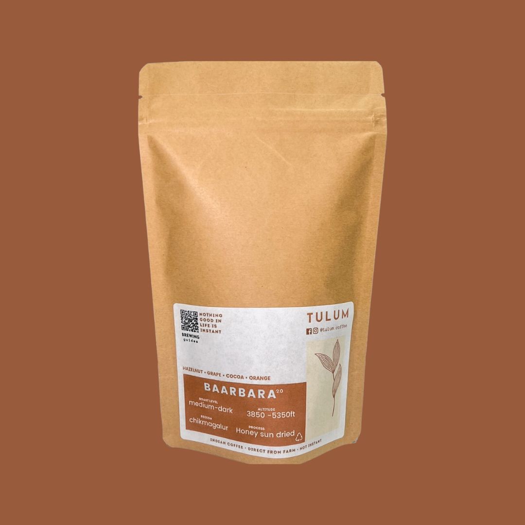 Close up view of Tulum's Baarbara - Arabica Coffee beans of 100 grams in brown packets with label highlighting Hazelnut and cocoa flavour notes